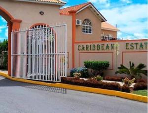 ein Gebäude mit einem weißen Tor davor in der Unterkunft Secure Gated 1BR Home in Caribbean Estate 2BR Also Available in Portmore