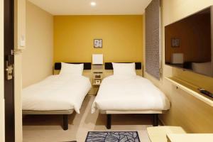 Zimmer mit 2 Betten und einem TV. in der Unterkunft Hotel Nihonbashi Saibo in Tokio