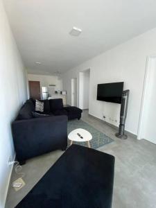 ein Wohnzimmer mit einem blauen Sofa und einem TV in der Unterkunft Sandstone Apartment a walk to the beach in Flic-en-Flac