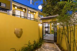 a yellow house with a mask on the wall at Hoi An Rosie Villa - 2 Bedrooms with Private Pool and Local Hoi An Decor in Hoi An