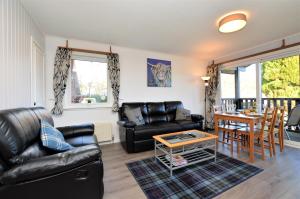 a living room with black leather furniture and a table at Holy Loch Lodge in Hunters Quay