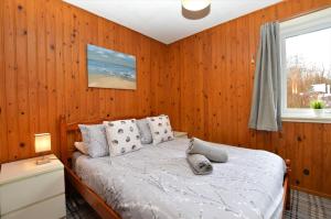 a bedroom with a bed with a wooden wall at Holy Loch Lodge in Hunters Quay