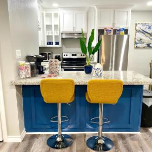 a kitchen with a blue island with two yellow bar stools at NEW! close to Downtown, Malls & Premium Outlets, with Balcony in Weslaco
