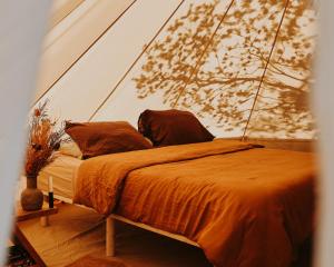 a bed with an orange comforter and pillows at Numie - Freycinet Peninsula - Glamping in Coles Bay