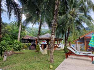 a resort with a hammock and two palm trees at Khaolak Banana Bungalow in Khao Lak