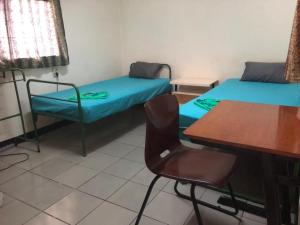 a room with two beds and a table and a chair at Unu Pikin Guesthouse in Paramaribo
