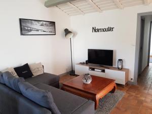 uma sala de estar com um sofá e uma televisão em La Villa du Tesselier em Noirmoutier-en-l'lle