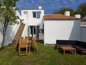 um quintal com uma mesa e cadeiras e uma casa em La Villa du Tesselier em Noirmoutier-en-l'lle