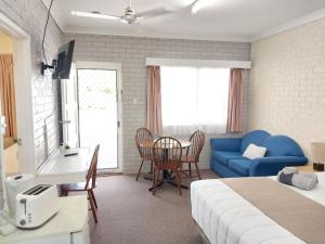 ein Schlafzimmer mit einem Bett, einem blauen Sofa und einem Tisch in der Unterkunft Jillaroo Motor Inn in Glen Innes