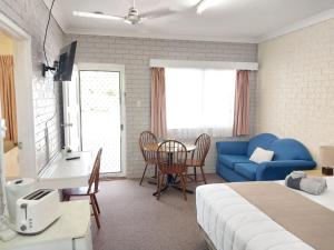 1 dormitorio con cama, sofá azul y mesa en Jillaroo Motor Inn, en Glen Innes