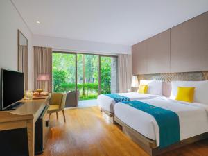 a hotel room with a bed and a desk and a television at Mövenpick Resort & Spa Jimbaran Bali in Jimbaran