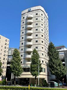 duży biały budynek z drzewami przed nim w obiekcie Olympic Inn Azabu w Tokio
