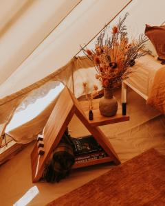 a bed in a tent with a vase of flowers at Numie - Freycinet Peninsula - Glamping in Coles Bay