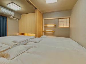 a bedroom with two beds with white sheets at 浅草寺3分｜浅草駅6分｜広い｜畳部屋付き｜2-14人｜成田&羽田空港直通 in Tokyo