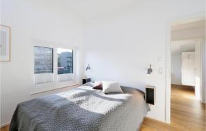 a white bedroom with a bed and two windows at Cozy Home In Lembruch-dmmer See With Sauna in Lembruch