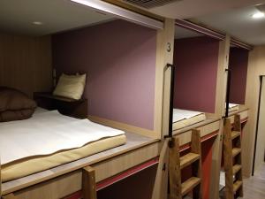two bunk beds are in a room with purple walls at Hotel Eco Dogo in Matsuyama