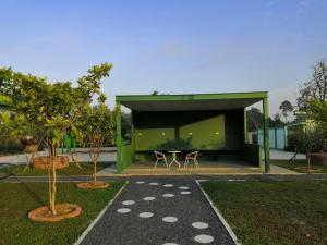 um edifício verde com uma mesa e cadeiras num quintal em NornD@Rayong em Ban Khao Yai Chum