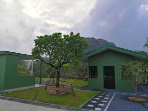a green building with a tree in front of it at NornD@Rayong in Ban Khao Yai Chum