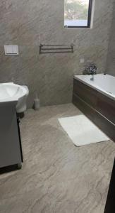 a bathroom with a sink and a tub and a toilet at Pisano Luxury Apartments in Lusaka