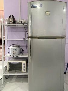 una nevera de acero inoxidable en una cocina con microondas en AR HOMESTAY & ROOMESTAY, en Merlimau