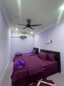a bedroom with a bed with purple sheets and a ceiling at AR HOMESTAY & ROOMESTAY in Merlimau