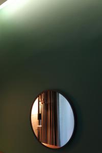 LE SEOUL HOTEL في سول: مرآة مستديرة على جدار أخضر مع مصباح