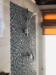 y baño con ducha y pared de azulejos negros. en FILAO EDEN SAKALAVA, en Antsiranana