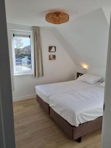 een slaapkamer met een bed en een raam bij Vakantiewoning 1 aan zee, 400 meter van het strand in Zoutelande