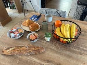 uma mesa com uma cesta de frutas e um prato de pão em Flo em Saint-Yan