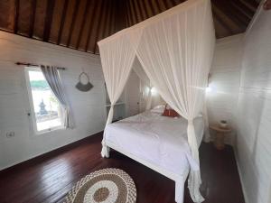 1 dormitorio con 1 cama blanca con dosel en The KUBU 221 en Lembongan