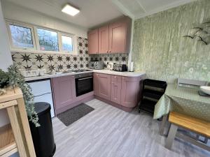 a kitchen with purple cabinets and a table and a dining room at Shrimpy- A cute family friendly chalet in Cromer in Cromer