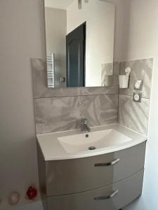 uma casa de banho com um lavatório branco e um espelho. em Flo em Saint-Yan