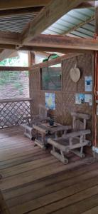 una habitación con bancos y mesas en una cabaña en Little Nomads eco-guesthouse, en Siquijor