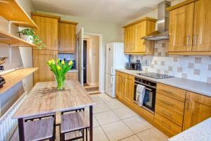 a kitchen with wooden cabinets and a table with flowers on it at Branch cottage in Limavady
