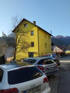 un grupo de coches estacionados frente a un edificio amarillo en Dogs baronesse Pasja grofica Idrija, en Idrija