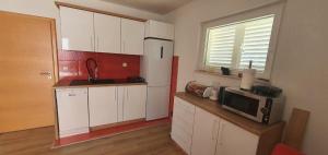 a kitchen with white cabinets and a microwave on a counter at Apartman Lejla in Orebić