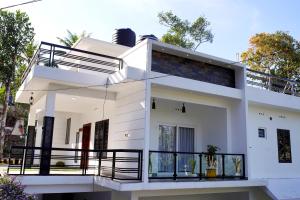 Cette maison blanche dispose d'un balcon. dans l'établissement Vaishnavam Home stay, à Thekkady