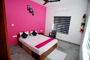- une chambre avec un mur rose et un lit dans l'établissement Vaishnavam Home stay, à Thekkady