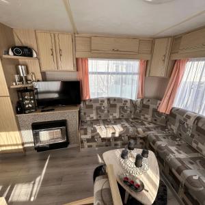 a living room with a couch and a table at Caravan 2 bedroom - New Camping Ideal in De Haan