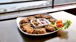 a plate of food with meatballs and vegetables on a table at Fewa View Cottage and Yoga Retreat Homestay in Pokhara