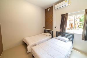two beds in a room with a window at J Villa Betong - Private House in Betong