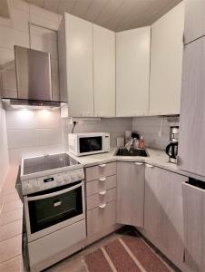 uma cozinha com armários brancos, um fogão e um micro-ondas em Studio Porin Otso, home away home in Pori city center em Pori