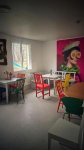 ein Zimmer mit bunten Stühlen und Tischen sowie einem Gemälde in der Unterkunft Orrefors Vandrarhem in Nybro