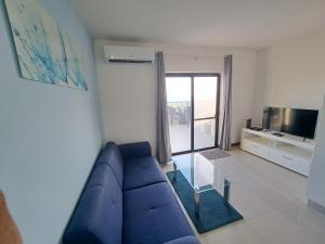 un salon avec un canapé bleu et une table en verre dans l'établissement Sea view penthouse, à Żebbuġ