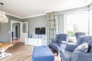 a living room with blue chairs and a tv at Ferienwohnung Hus up Höcht in Langeoog