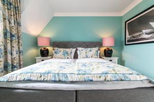 ランゲオークにあるLieblingsinsel Langeoogの青い壁のベッドルーム1室、ベッド1台(ランプ2つ付)
