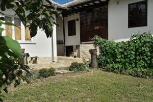 une maison avec une terrasse couverte et une cour fleurie dans l'établissement Lomtsi Popovo Targovhiste Bulgarije, à Lomtsi