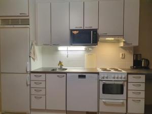 a kitchen with white cabinets and a sink and a microwave at Lovely Two Room Apartment in Helsinki in Espoo