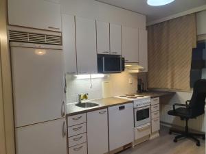 a kitchen with white cabinets and a sink and a chair at Lovely Two Room Apartment in Helsinki in Espoo