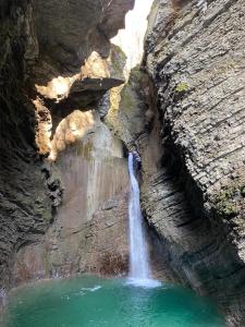 a waterfall in a canyon with a pool of water at Hotel Hvala Superior - Topli Val in Kobarid